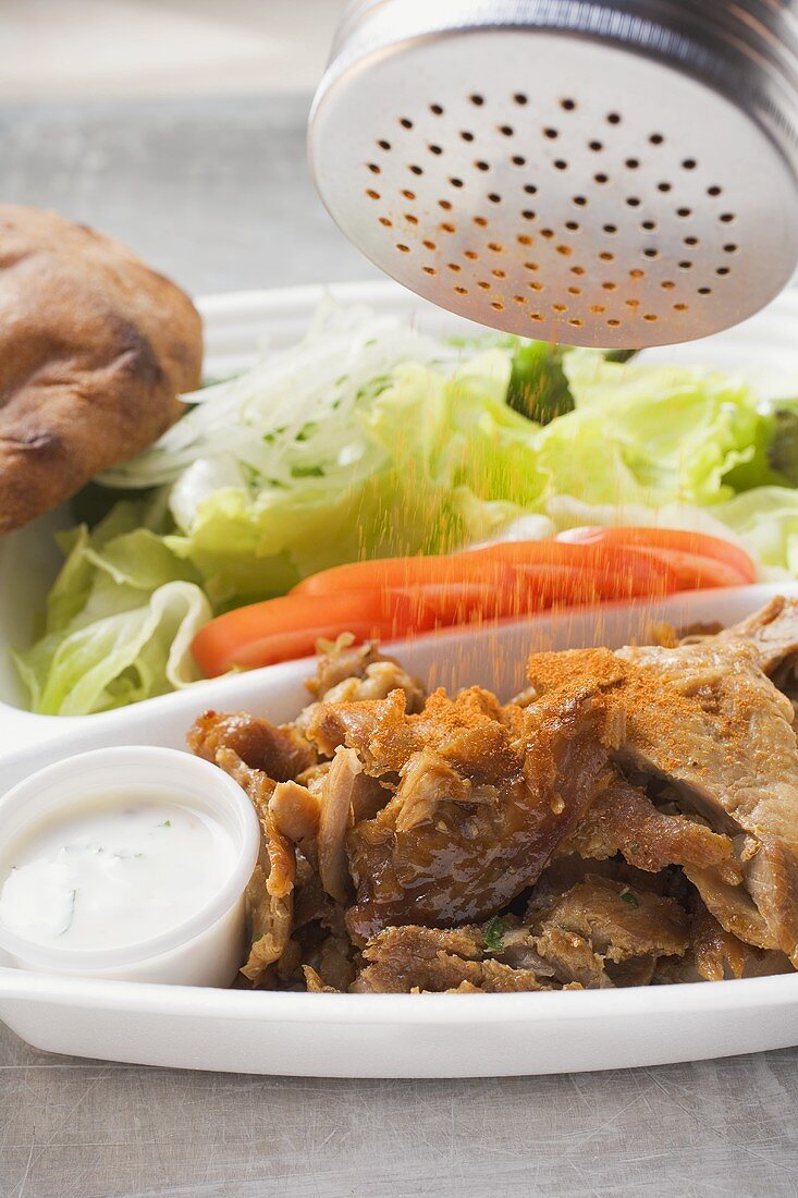 Döner Kebab in Lunchbox mit Gewürz bestreuen