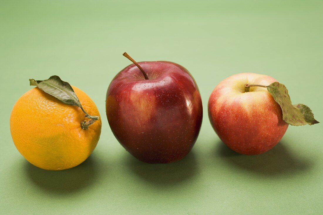 Zwei rote Äpfel, Sorte Stark und Elstar, und Orange