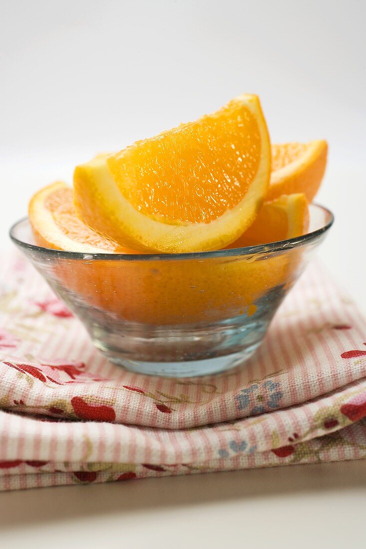 Several orange wedges in glass bowl on cloth