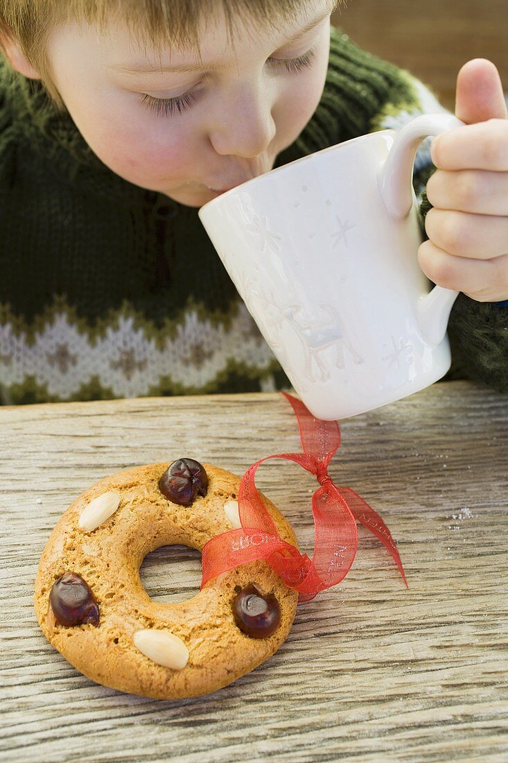 Small boy drinking hot drink, gingerbread tree ornament