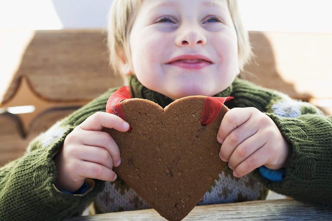 A small boy with a Christmassy gingerbread heart