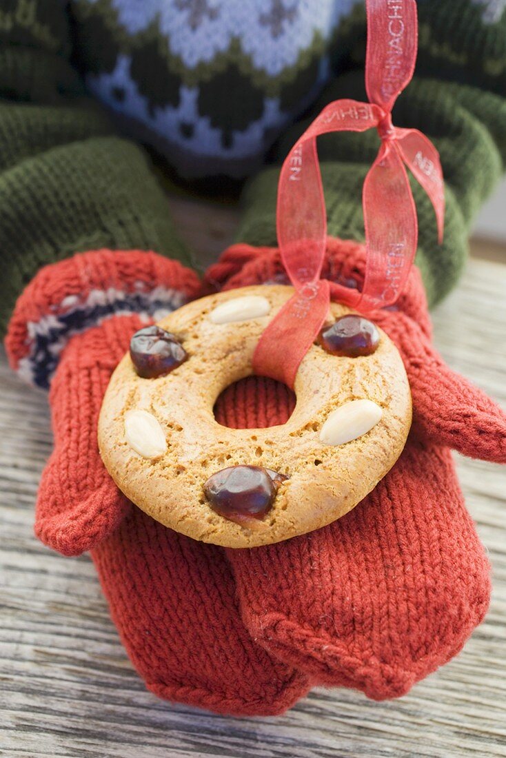 Child's hands in mittens holding gingerbread tree ornament