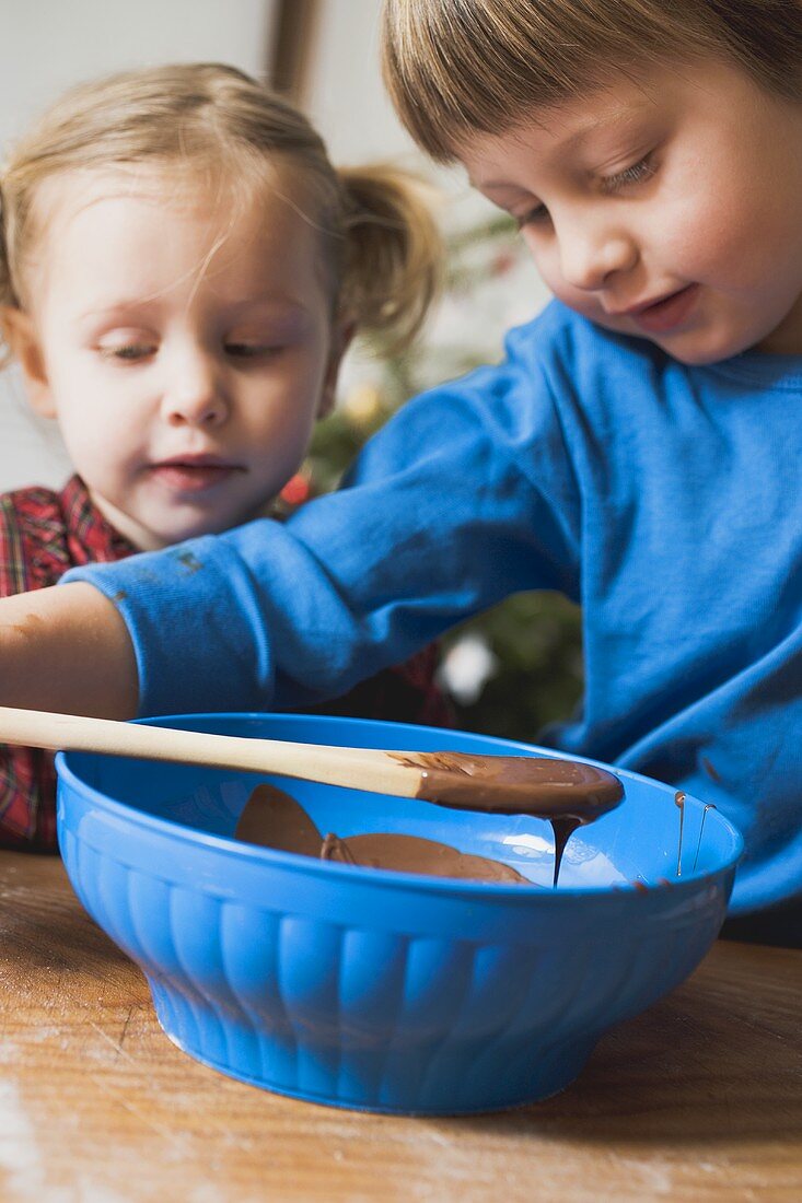 Zwei Kinder bereiten Schokoladenglasur zu
