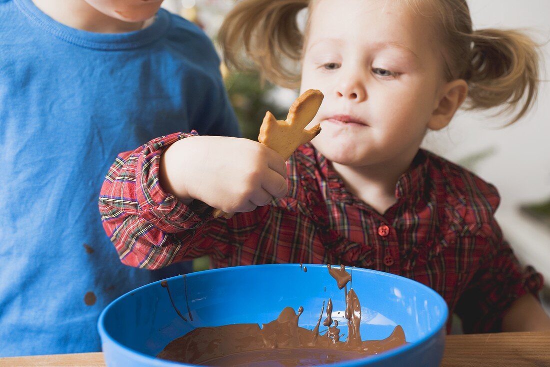 Girl dipping Christmas biscuit in chocolate icing