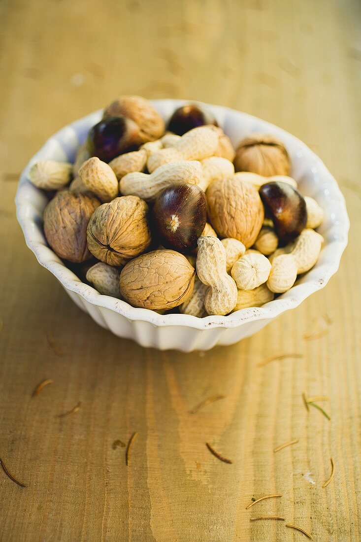 Walnuts, chestnuts and peanuts in white bowl