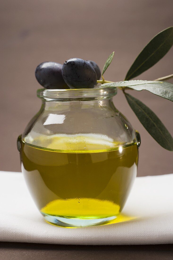 Schwarze Oliven am Zweig auf Glas Olivenöl