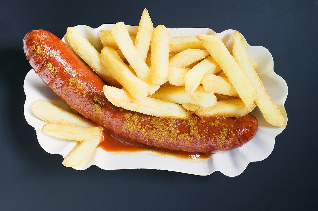 Currywurst mit Pommes frites und Ketchup auf Pappteller