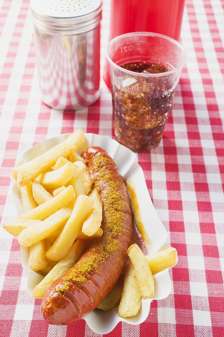 Sausage with ketchup & curry powder with chips in paper dish, cola