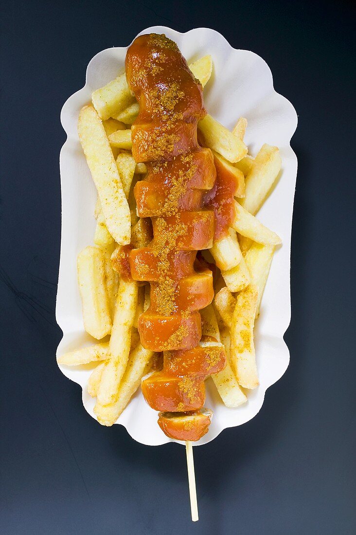 Currywurst mit Pommes frites auf Pappteller