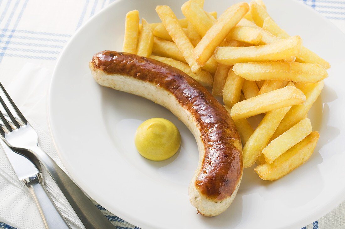 Sausage with chips and mustard on plate