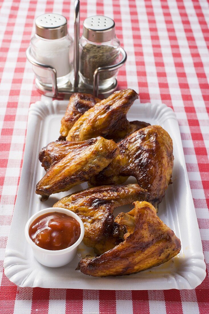 Grilled chicken wings with ketchup on paper plate