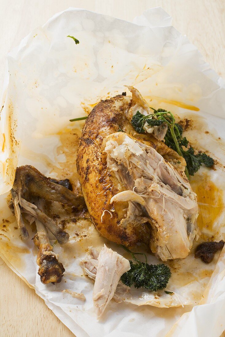 Half a roast chicken with parsley, partly eaten