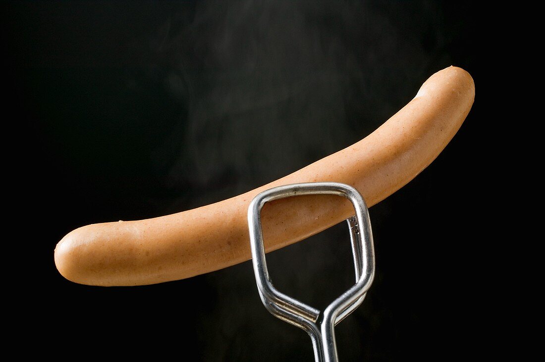 Tongs holding frankfurter