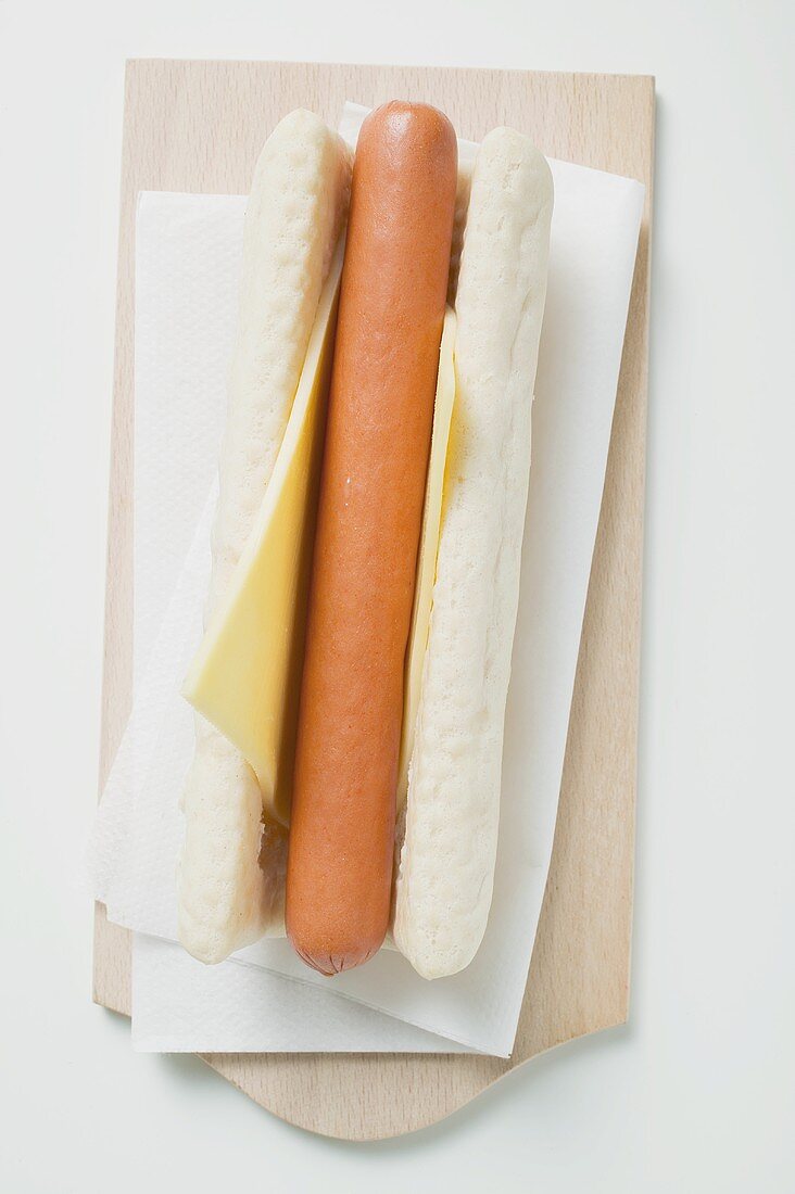 Hot dog with cheese on chopping board