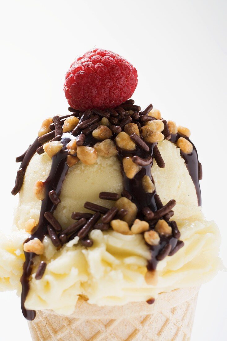 Cone of nut ice cream with chocolate sauce and raspberry