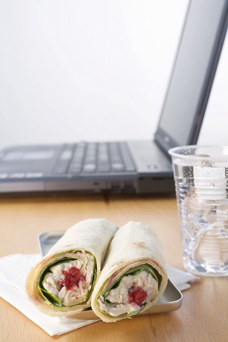 Tuna wraps and mineral water in front of laptop