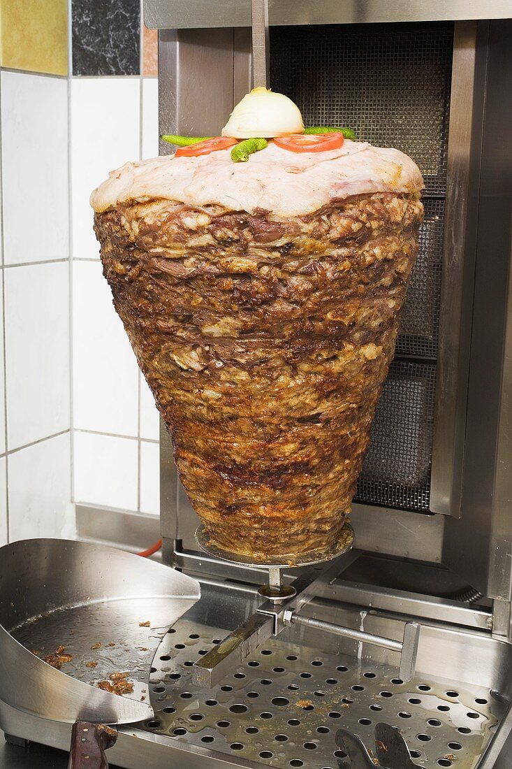 Döner kebab meat on spit in front of grill in restaurant