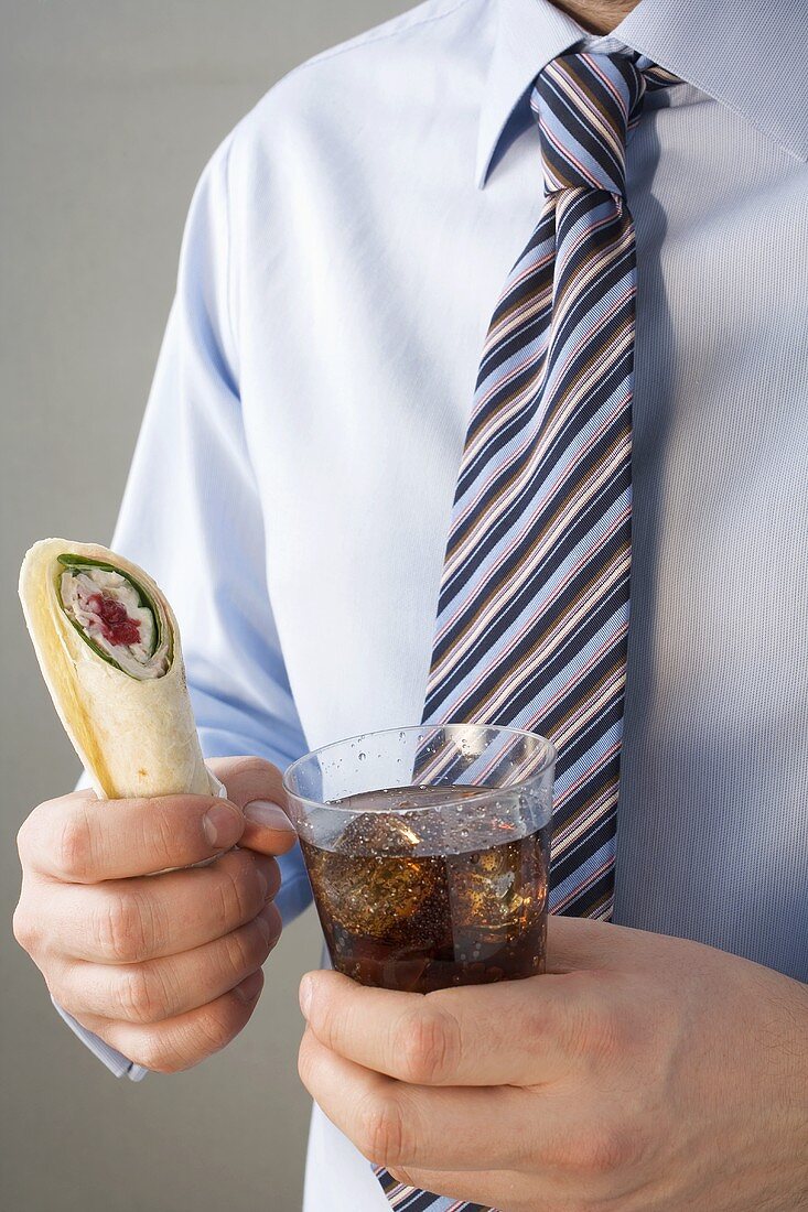 Mann mit Krawatte hält Wrap und Cola