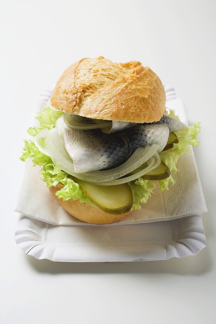 Heringsbrötchen mit Zwiebeln und Essiggurken auf Pappteller