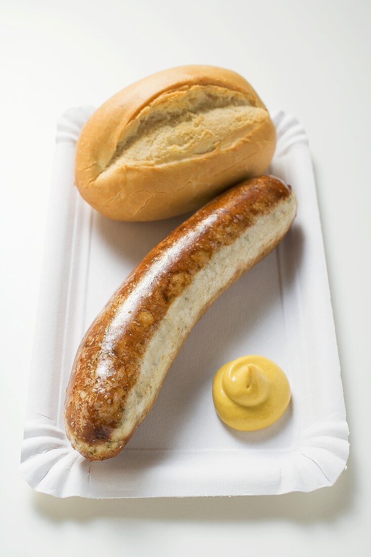Sausage with mustard and baguette roll on paper plate