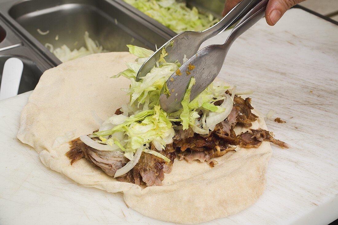 Making a döner wrap (topping with lettuce)