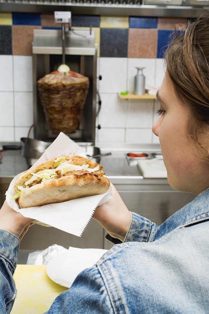 Teenager with döner kebab in kebab shop