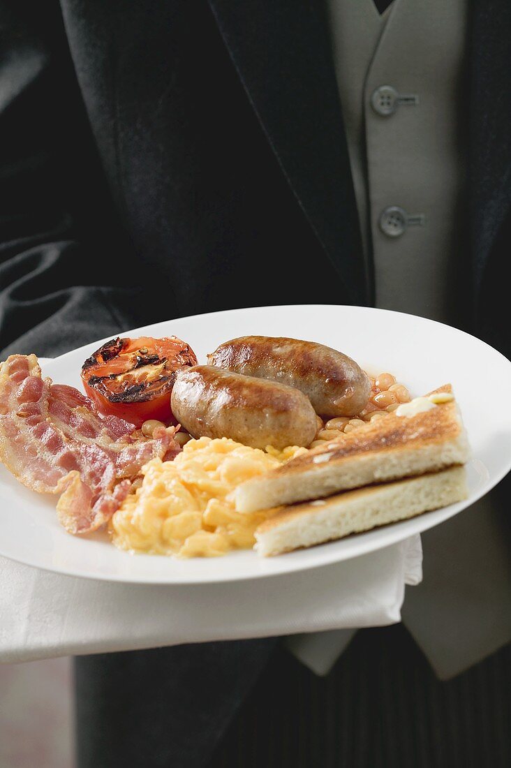 Butler serving English breakfast on plate