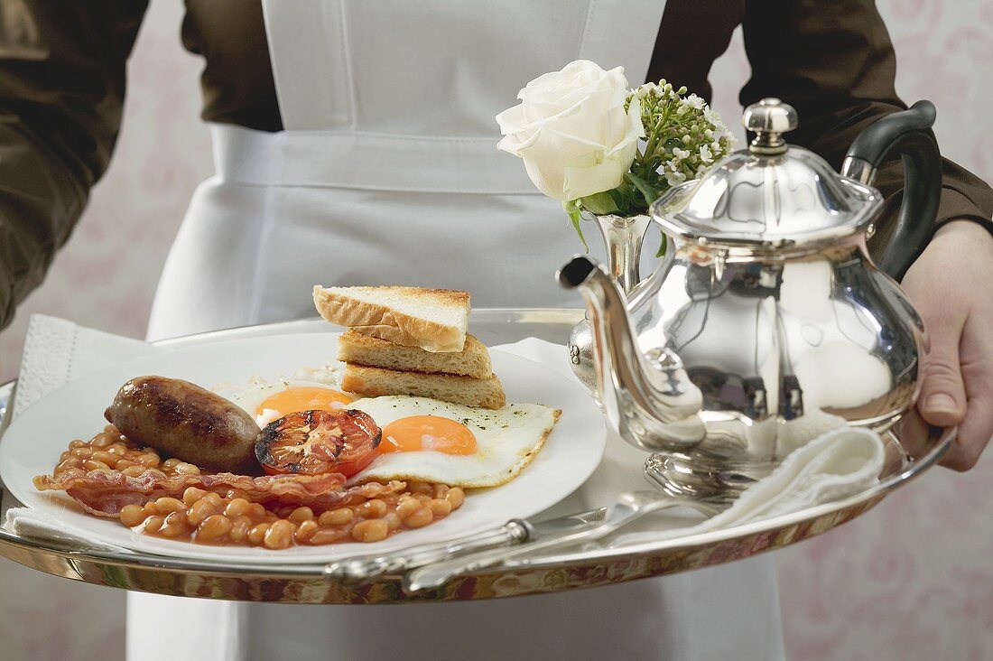 Zimmermädchen serviert englisches Frühstück auf Tablett