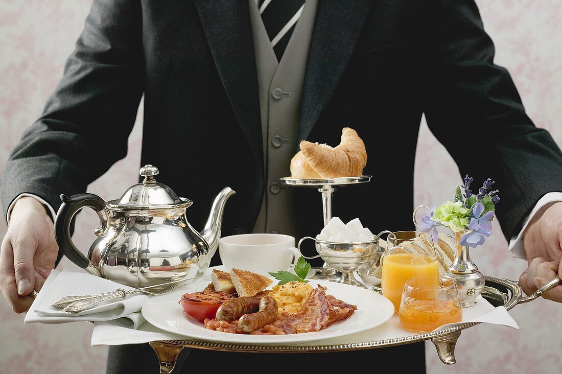 Butler serving English breakfast on tray