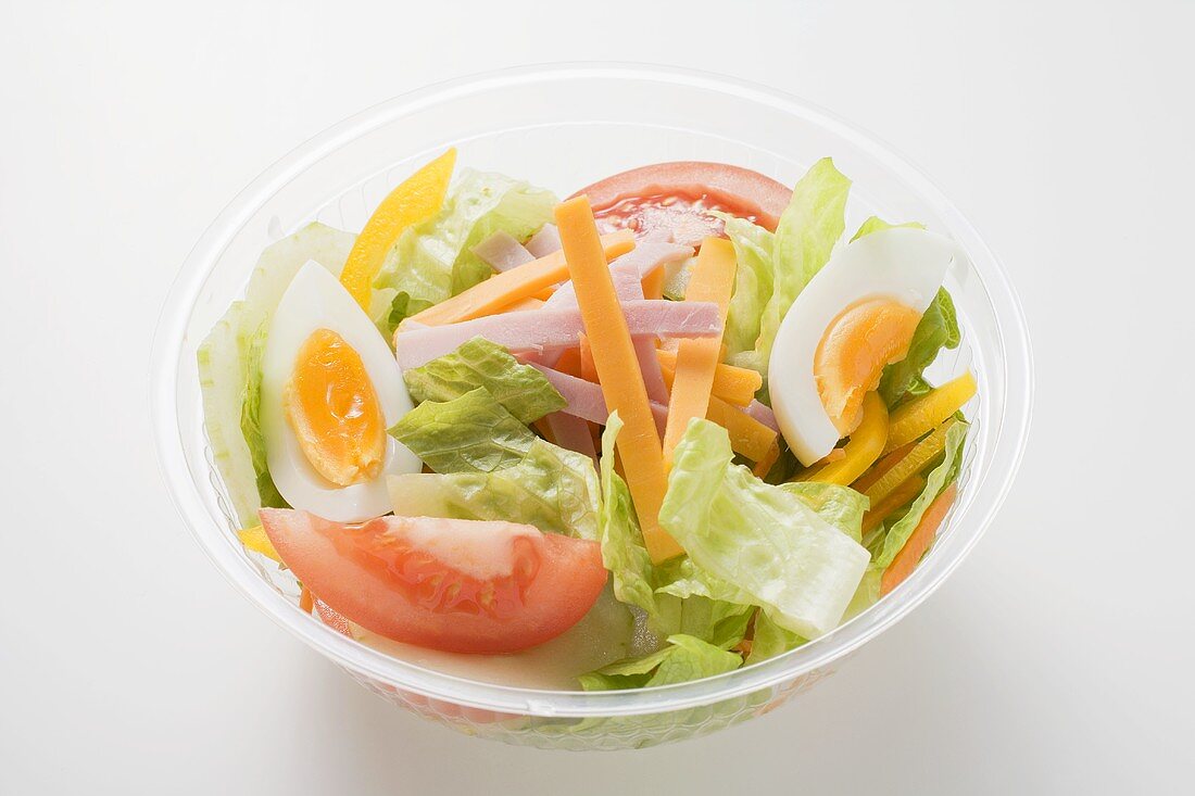 Eissalat mit Schinken, Käse, Ei und Tomaten in Plastikschale