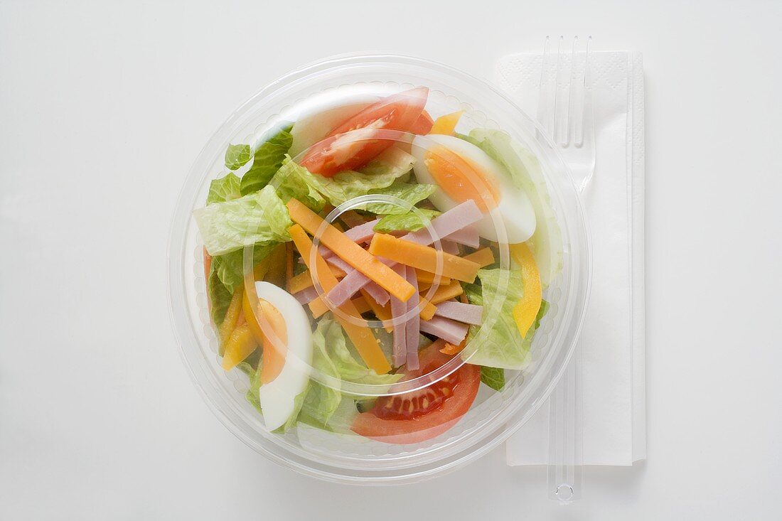 Iceberg lettuce, ham, cheese, egg & tomatoes in plastic bowl