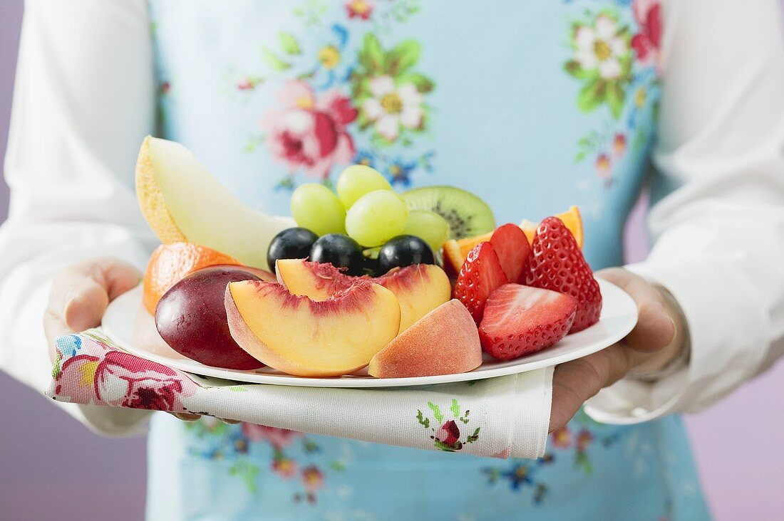 Woman serving a plate of fresh fruit