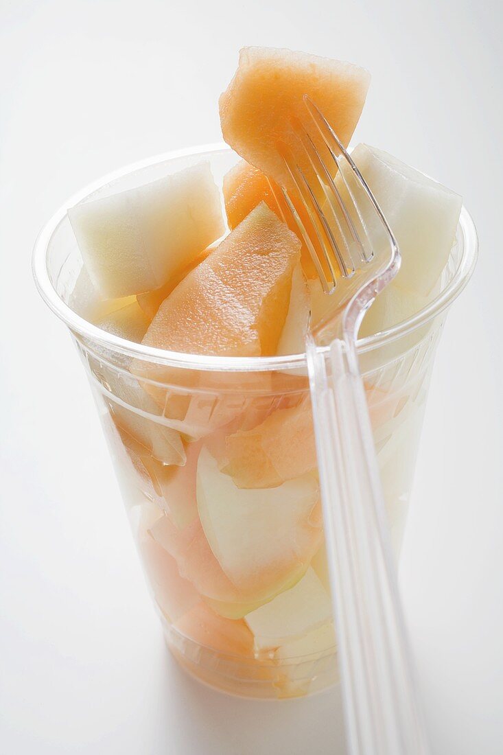 Fruit salad in a plastic beaker with a fork