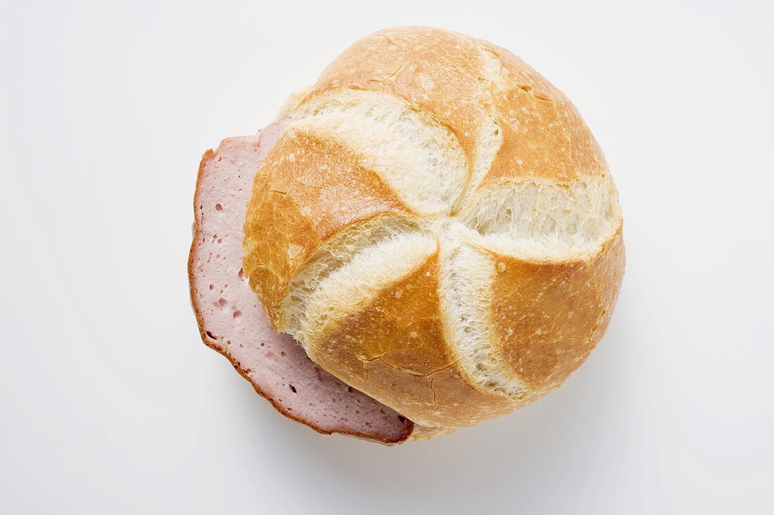 Slices of Leberkäse (a type of meatloaf) in a roll from above