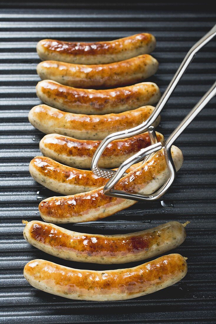 Grilled sausages from above with tongs
