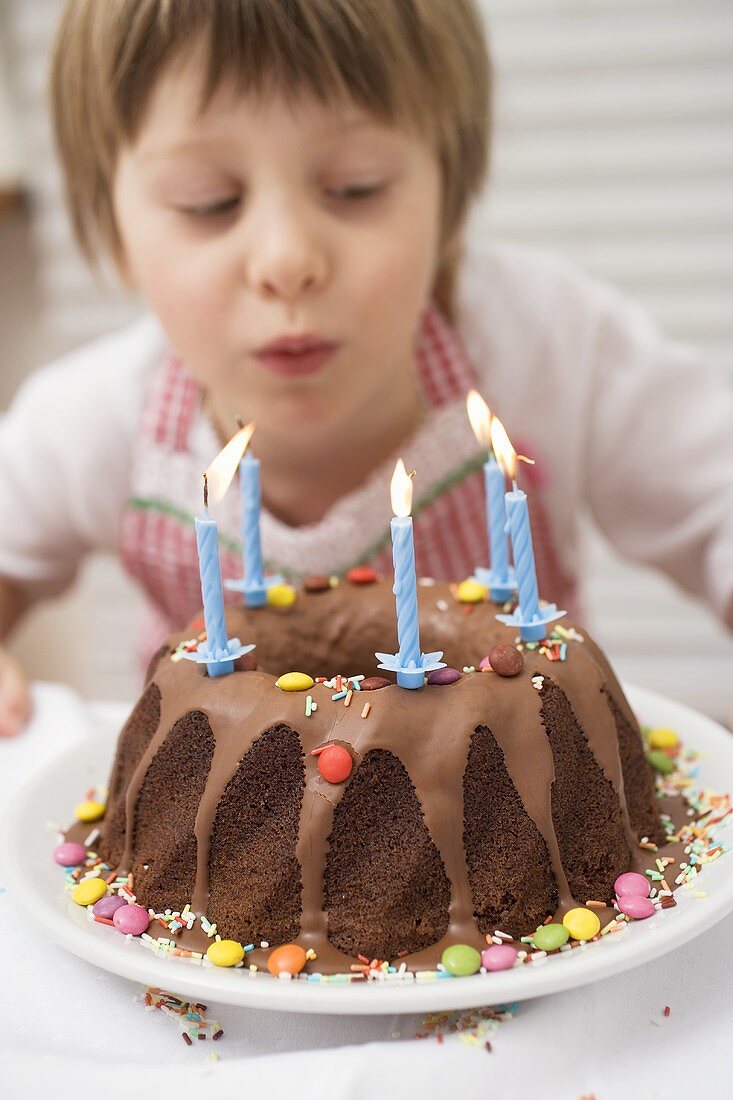 Small boy blowing out candles on birthday cake