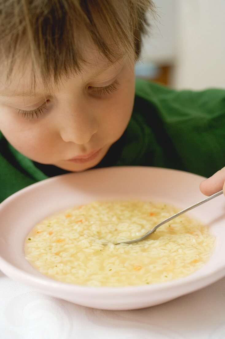 Small boy eating noodle soup