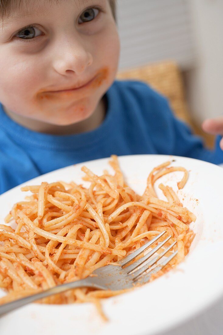 Kleiner Junge isst Nudeln mit Tomaten