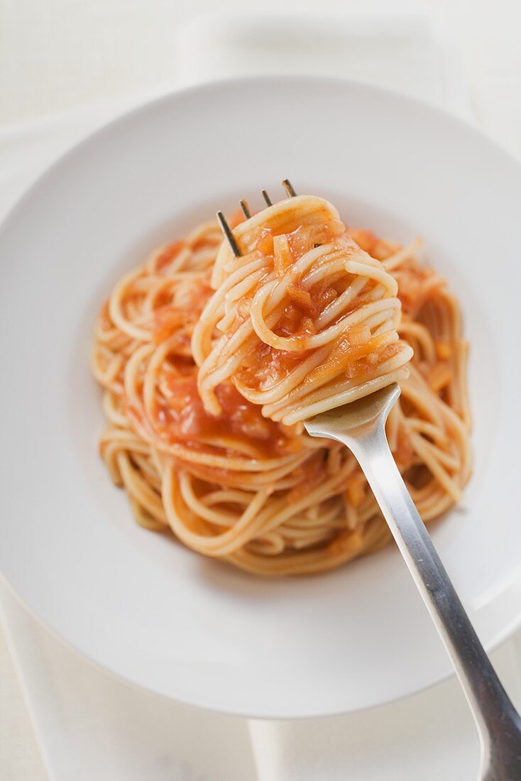 Spaghetti mit Tomatensauce auf Gabel und Teller