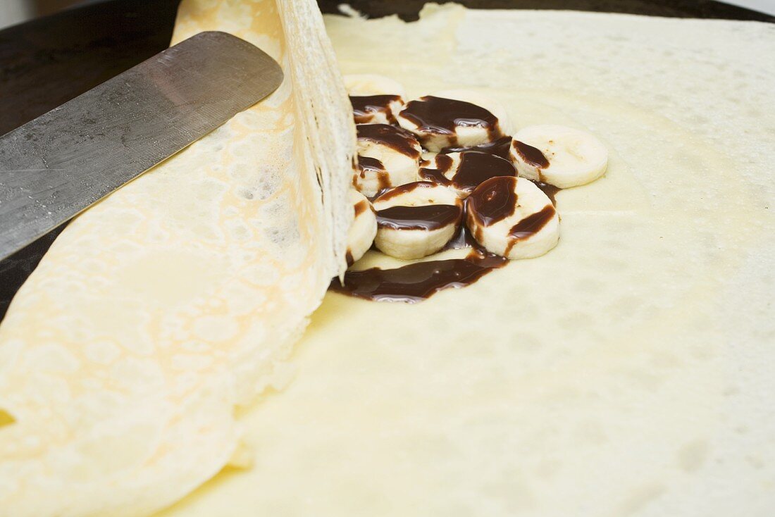 Folding a crêpe with banana and chocolate filling