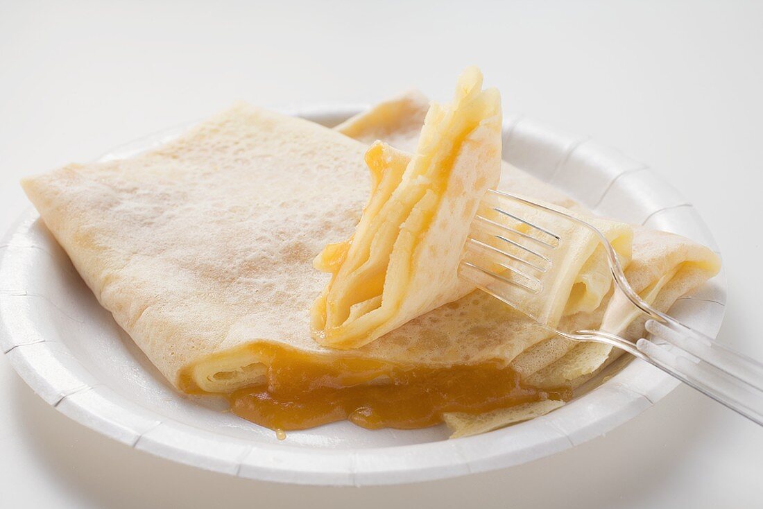 Crêpes with apricot jam on paper plate