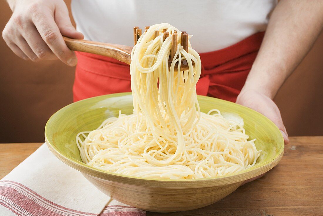 Gekochte Spaghetti mit Spaghettiheber anheben