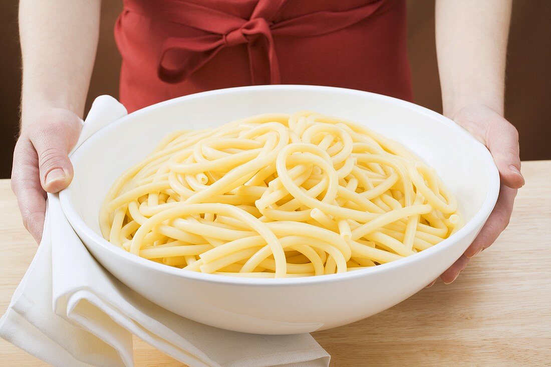 Woman holding bowl of cooked macaroni