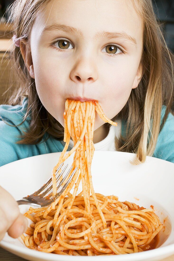 Mädchen isst Spaghetti mit Tomatensauce