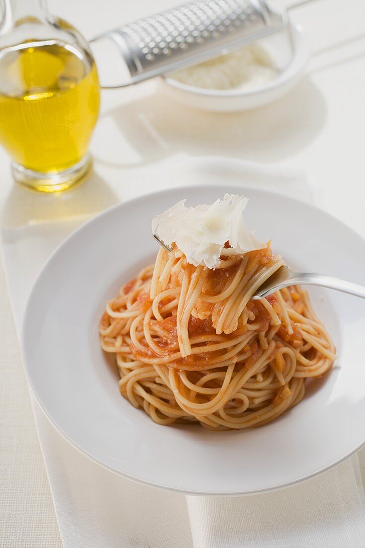 Spaghetti mit Tomatensauce und Parmesan auf Gabel und Teller