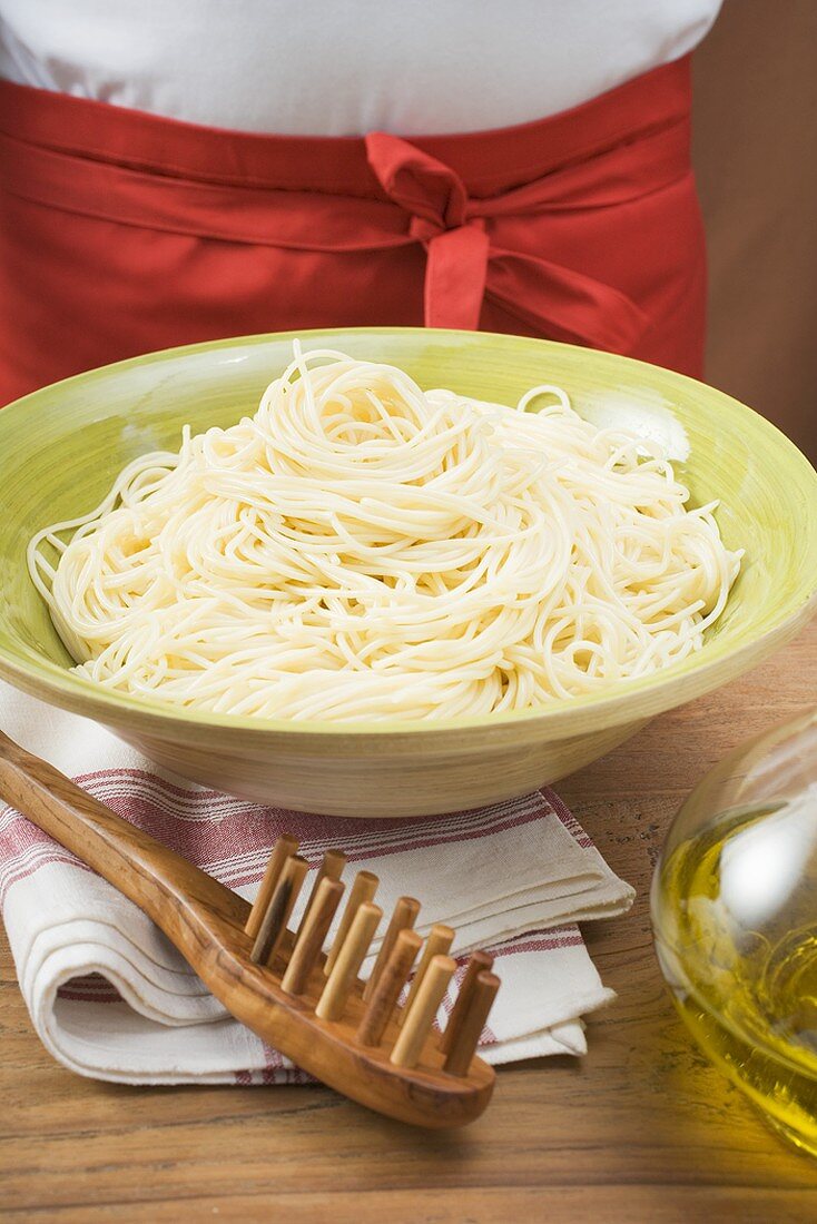 Gekochte Spaghetti in Schüssel, daneben Spaghettiheber