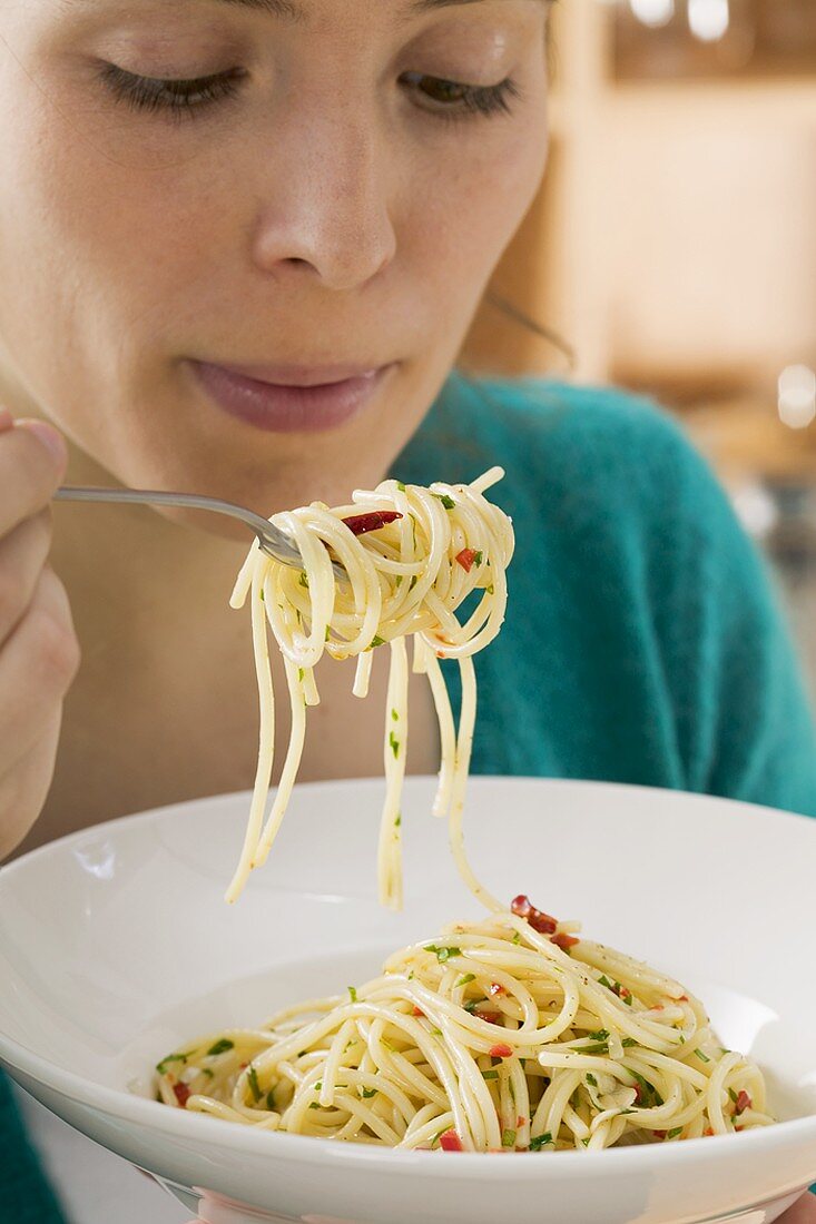 Junge Frau isst Spaghetti mit Chilischoten