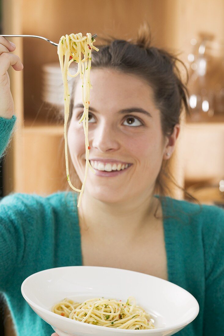 Young woman eating spaghetti with chillies