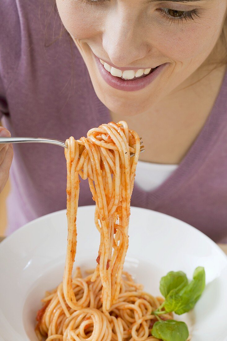 Woman eating spaghetti with tomato sauce