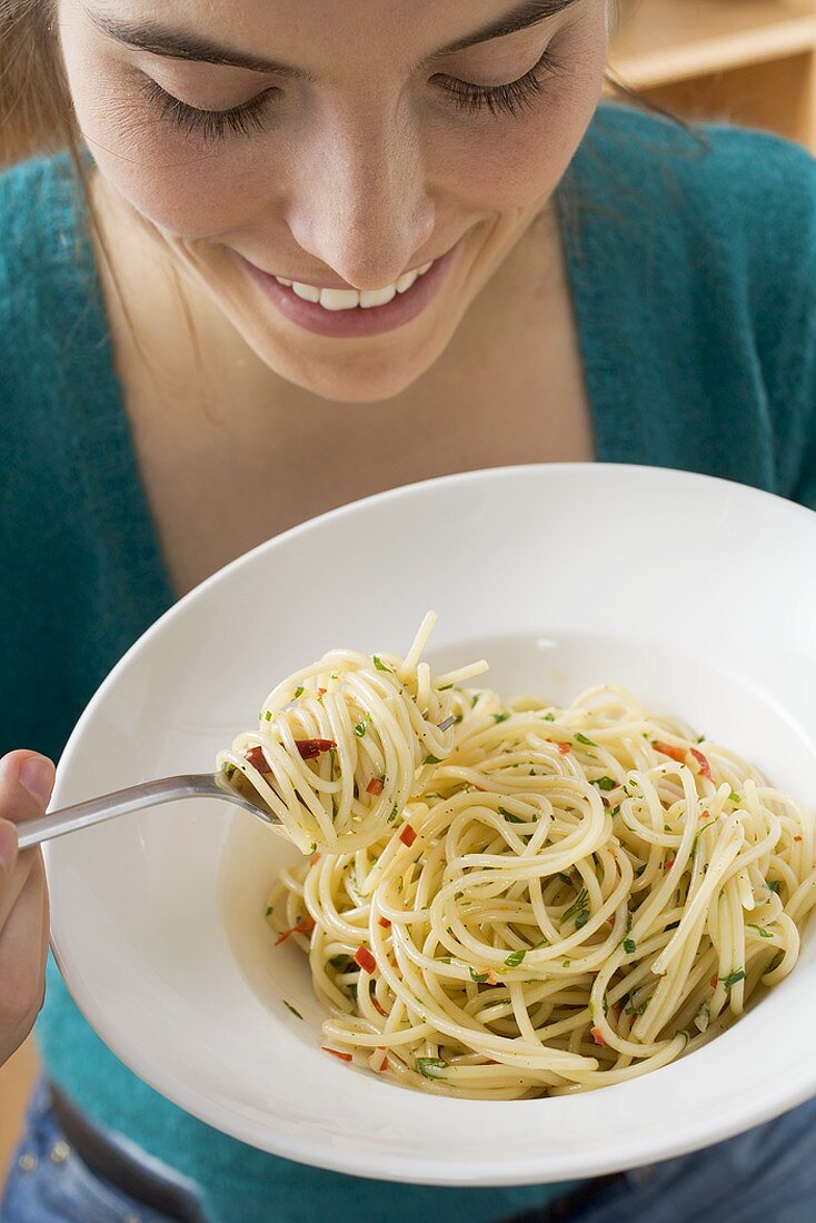 Junge Frau isst Spaghetti mit Chilischoten